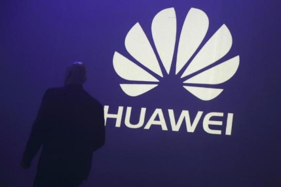 A man walks past a logo during the presentation the Huawei