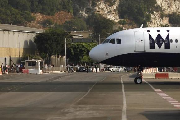 Pedestrians and drivers wait to cross the road of the Gibraltar International airport