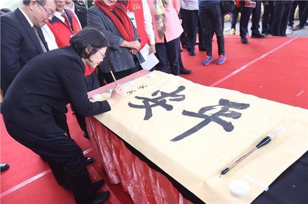 蔡英文在書法家張炳煌的「平安」墨寶上落款簽名。(圖：民進黨提供)