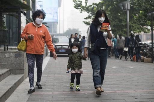 空氣品質相當差，民眾也只好帶著口罩上街。 (圖:AFP)