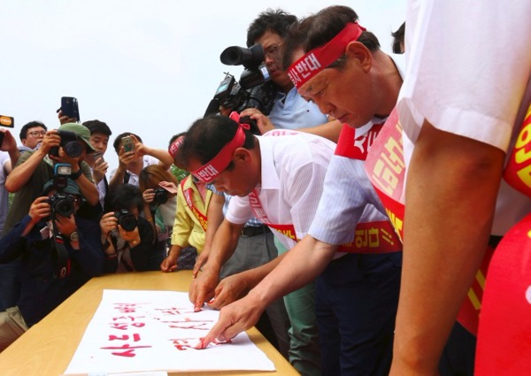 星州郡守金恒坤(右)和居民昨日集體割破指頭寫血書，抗議在星州部署薩德系統。  (圖：AFP)