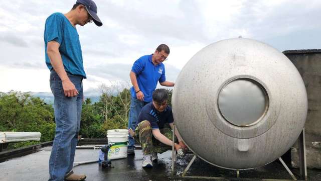 花蓮職業訓練場場長蕭志村(蹲者)與水電班結訓學員協助牛犁社區發展協會配置不鏽鋼水塔給水管管材，讓供水恢復正常（圖：勞動部提供)