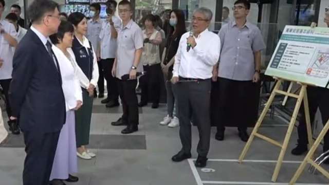 行政院卓榮泰(左1) 聽取國家住都中心董事長花敬群(執麥克風者)簡報。(直播截圖)