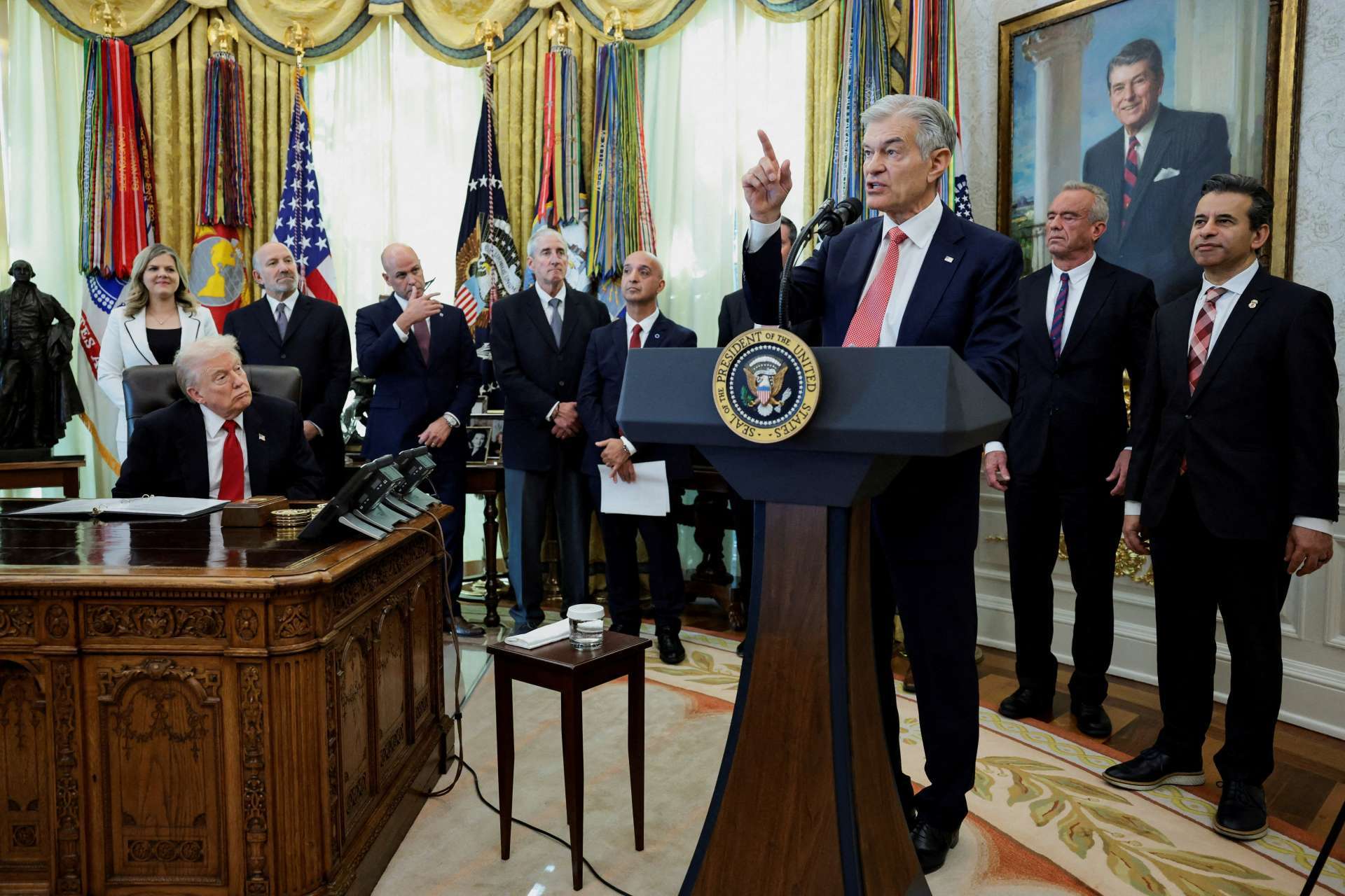 美國總統川普傾聽聯邦醫療保險與醫療補助服務中心（CMS）主任Mehmet Oz發言。該活動由川普主持，宣布與禮來製藥（Eli Lilly）及Novo Nordisk達成協議，將下調GLP-1類減重藥物的價格。地點為美國華盛頓白宮橢圓形辦公室，攝於2025年11月6日。REUTERS/TPG